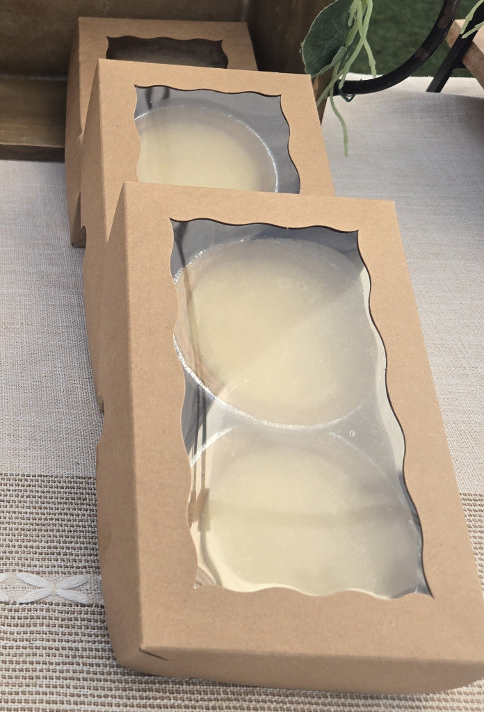 Two cardboard boxes with clear windowed fronts containing round objects on a textured surface.