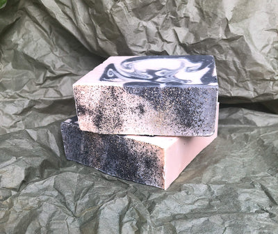 Two hexagonal soap bars with marbled design on a crumpled green paper background