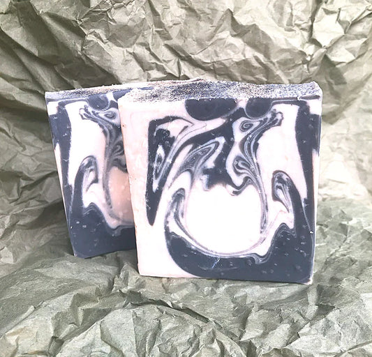 Two bars of soap with black and white marbled pattern on crumpled green paper.