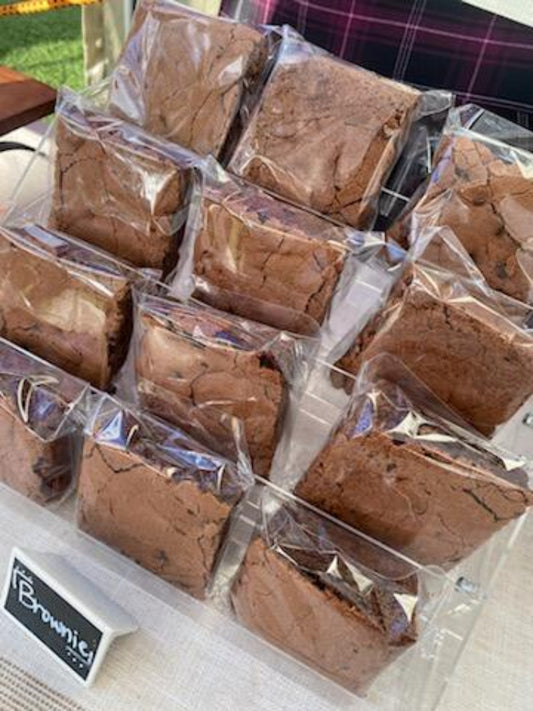 Brownies in clear packaging on a white surface with grass in the background